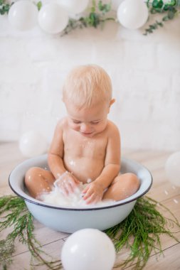 Tatlı küçük çocuk sabunlu su ve sabun köpüğüyle havuza su sıçratıyor. Sağlıklı çocukluk