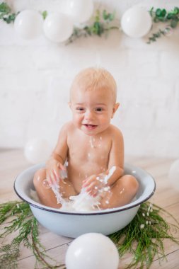 Tatlı küçük çocuk sabunlu su ve sabun köpüğüyle havuza su sıçratıyor. Sağlıklı çocukluk