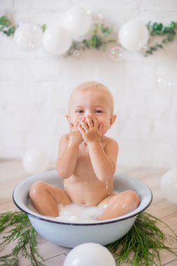 Tatlı küçük çocuk sabunlu su ve sabun köpüğüyle havuza su sıçratıyor. Sağlıklı çocukluk