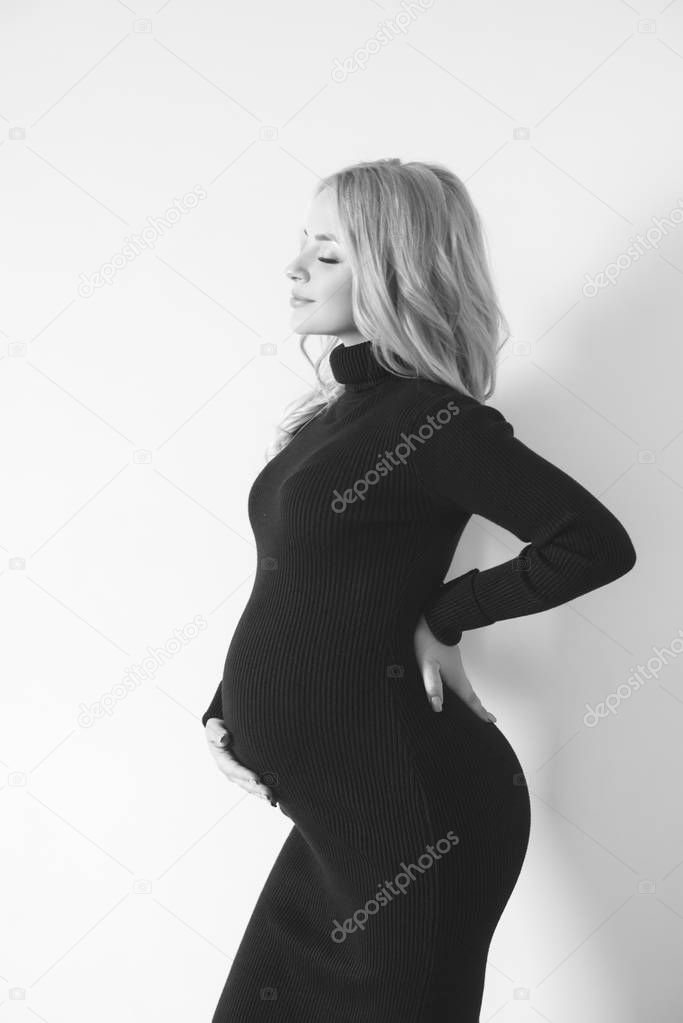 Attractive young woman with blond pregnant hair in a dark dress. Healthy happy pregnancy