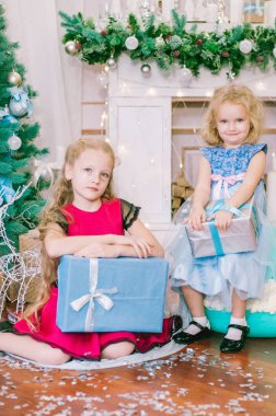 Beyaz balo elbisesi içinde, Noel ağacının yanında, hediye ve gümüş konfetiyle güzel, sarı saçlı kızlar. Noel havası