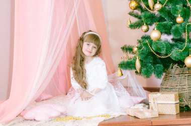 Noel ağacının yanındaki beyaz balo elbisesi içinde, hediyeli ve gümüş konfetiyle uzun saçlı tatlı bir kız. Noel havası