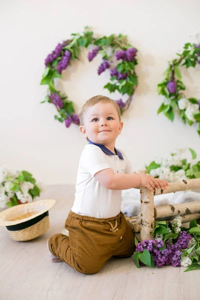春天的工作室里 一个小男孩 装饰着紫丁香花和柠檬 绽放的春天 — 图库照片