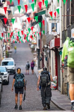 Pilgrims with backpack walking the Camino de Santiago, Saint Jean Pied de Port in Pays Basque, France clipart