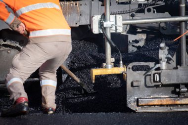 Yolda asfalt sıkıştıran tekerlekli bir işçi