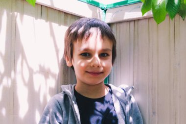 Güneşli bir günde bir ağacın altında duran bir çocuğun portresi. Yüzündeki ışık ve gölge oyunu.