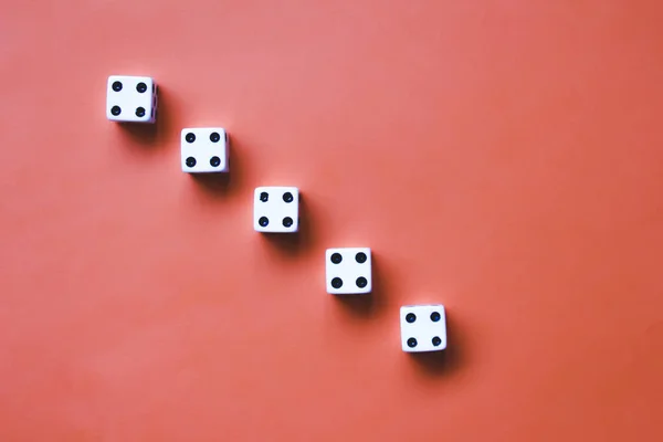 Five white dice on an orange background. Concept: dice poker, gambling. Combination: Combination: Poker on four