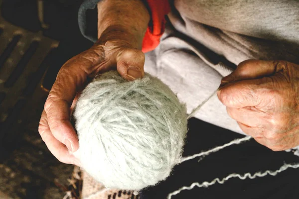 Grandmother is holding a yarn for knitting