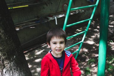 Büyükannesinin bahçesinde kırmızı kazaklı küçük bir çocuğun portresi.