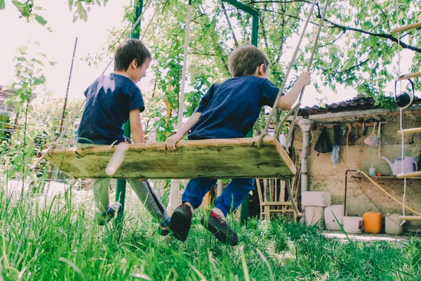 Dos Niños Pequeños Balancean Juntos Columpio Jardín —  Fotos de Stock