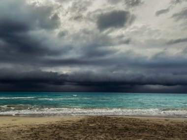 Turkuaz okyanusun üzerinde koyu gri bulutlar ile alçak fırtınalı gökyüzü