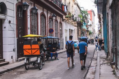 Havana, Küba, Şubat 2020: Turistler ve bisiklet taksileri eski Havana sokaklarında