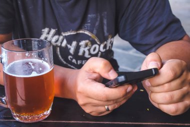 Havana, Küba, Şubat 2020: Bir adam telefonu elinde tutuyor, sıradaki bira bardağı.