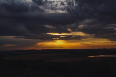 Batan güneşin altın ışığı bulutları delip geçer.