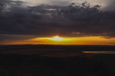 Batan güneşin altın ışığı bulutları delip geçer.