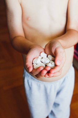 Çocuk, hayvan şeklinde beyaz çiğnenebilir vitaminler tutuyor.