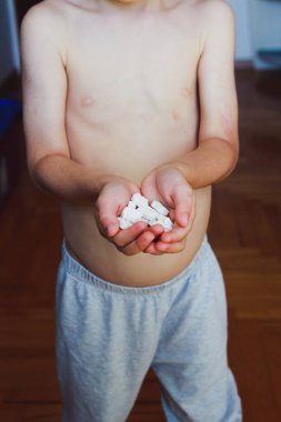 Çocuk, hayvan şeklinde beyaz çiğnenebilir vitaminler tutuyor.