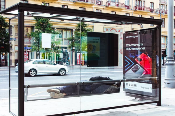 Moskova, Rusya, 2 Ağustos 2020: Moskova 'da Tverskaya Caddesi' ndeki otobüs durağında bir adam yatıyor.
