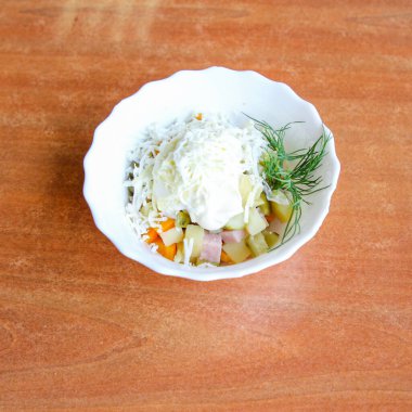 Jambonlu Olivier salatası kahverengi ahşap bir masada.