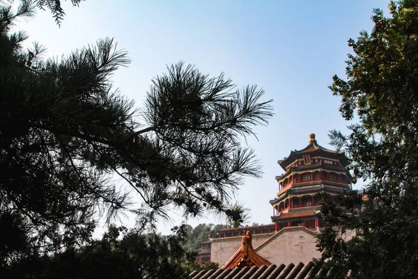 Yiheyuan Parkı 'ndaki Çin imparatorlarının evinin tepesindeki yeşil ağaçlar tarafından çerçevelenmiş bir pagoda.