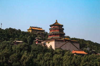 Yiheyuan Parkı 'ndaki Çin imparatorlarının evinin tepesindeki yeşil ağaçlar tarafından çerçevelenmiş bir pagoda.
