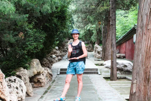 Pekin, Çin, 1 Ağustos 2018: Pekin Parkı 'ndaki taşların ve ağaçların arasında poz veren kız turist