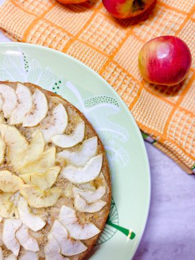 Tabakta elmalı turta var, kırmızı elmaların yanında.