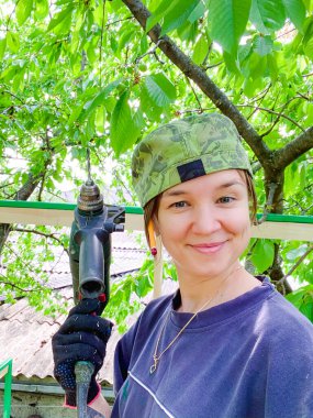 Şapkalı kız elinde matkap tutuyor.