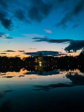 Gece manzarası: Ostankino gölünün pürüzsüz yüzeyinde günbatımı ışınlarının ve bulutların yansıması