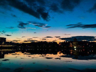 Gece manzarası: Ostankino gölünün pürüzsüz yüzeyinde günbatımı ışınlarının ve bulutların yansıması