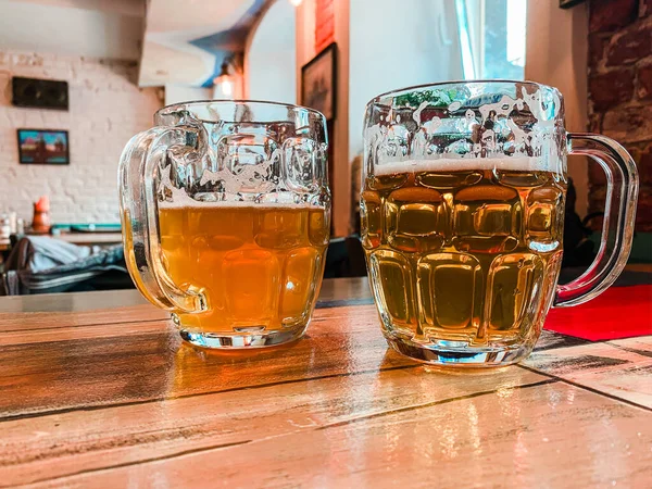 Tahta bir masada iki kupa bira var.