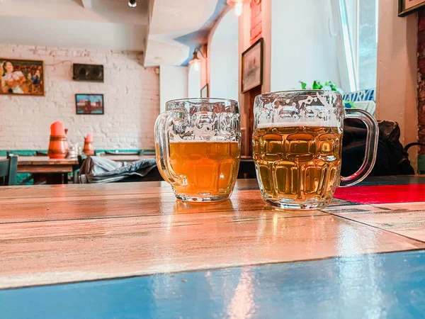 Tahta bir masada iki kupa bira var.