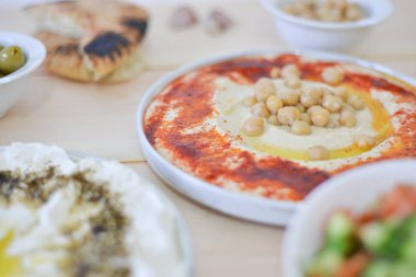Geleneksel ev yapımı humus rustik masa arka plan kırmızı kırmızı biber zeytin yağı, sarımsak, limon, tahin ve pide ekmek ile görüntü üzerinde tabak