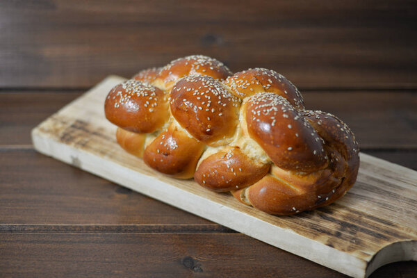 Traditional Jewish sweet Challah bread on a wood plate on wooden table / background with copy space