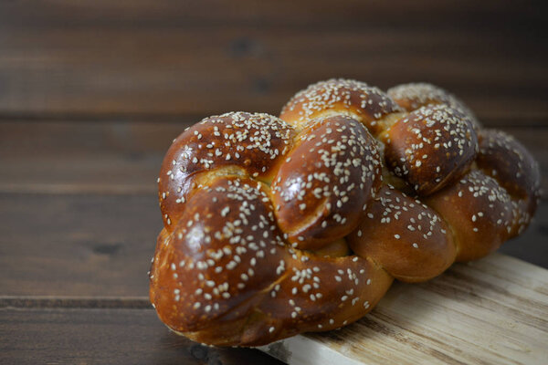 Traditional Jewish sweet Challah bread on a wood plate on wooden table / background with copy space