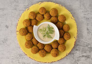 Nohut falafel topları sarı plaka gri arka plan, sağlıklı ve vegan gıda tahin derin, geleneksel Akdeniz üzerinde pişmiş, üstten görünüm, düz kopya alanı ile yatıyordu