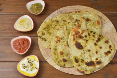 Geleneksel Hint Naan ekmek bazı salata küçük tabaklar ahşap zemin üzerine: labneh, humus ve matbucha (Fas domates salatası), flay kopya alanı ile yatıyordu üstten görünüm 