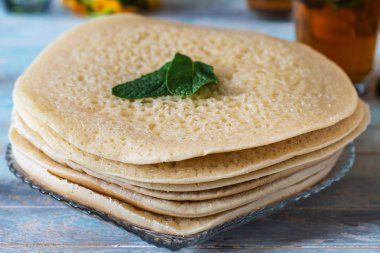 yakın Fas krep Baghrir veya crapes bal ile servis 1000 delikli arka plan çiçekler ile nana ile çay 