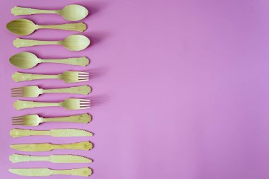 bambu kaşık ve çatal pembe veya mor arka plan üzerinde bir satır