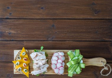 Sebze ile sağlıklı açık sandviçler, salatalık turp hindi pastırma peyniri ve ahşap arka plan üzerinde yumuşak peynir , üst görünüm , düz kopyalama alanı ile yatıyordu