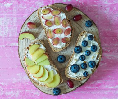 Meyve ile sağlıklı açık sandviçler, şeftali üzüm yaban mersini ve pembe ahşap arka plan yumuşak peynir , üst görünüm , düz yatıyordu