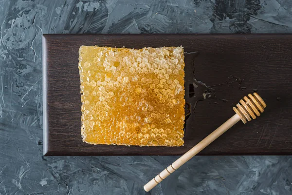 Méhsejt barna tányéron, szürke, fekete háttérrel — Stock Fotó