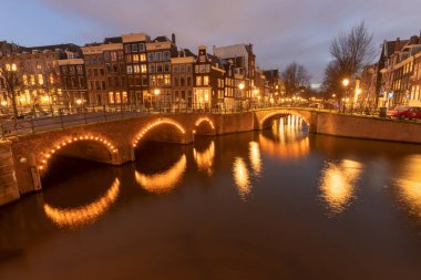 AMSTERDAM / HOLLLAND - HAZİRAN 05 2019: Bu, Amsterdam şehrinin akşam veya gece geç saatlerde çekilmiş görüntüsü. Ateş edildiği sırada gemi kanallardan geçmiş..