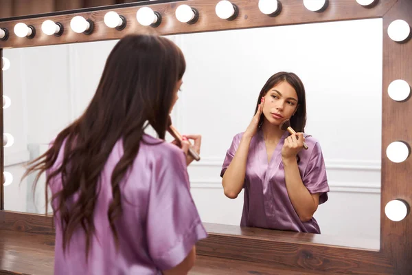 Prosedur make-up. Wanita muda dilukis di depan cermin. Konsep perlakuan kecantikan. — Stok Foto