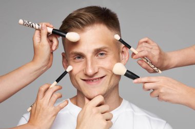 Erkek makyajı için makyaj malzemeleri. Yüz estetiği. Bir fırçayla kadın eli Mans 'ın yüzüne dokun