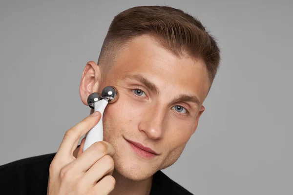 Jade Roller. Bir adamın yüzüne masaj yap. Yaşlanma önleyici kozmetik prosedür. Cilt Bakımı İşlemi.