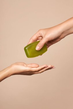 Hijyen. Kadın eli bej arka planda sabunu uzatır. Viral ve bakteriyel enfeksiyonları önlemek için günlük hijyen.