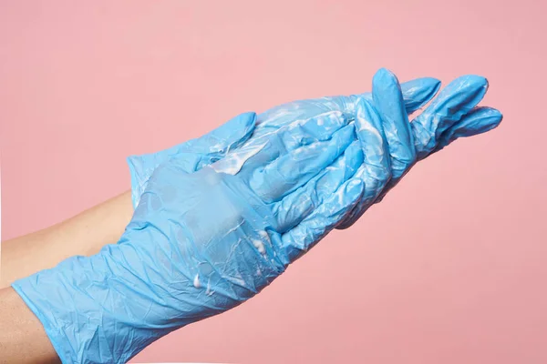Higiene. As mãos femininas com luvas traem desinfetam-se em um contexto rosa. Lavagem das mãos para salvar uma vida — Fotografia de Stock