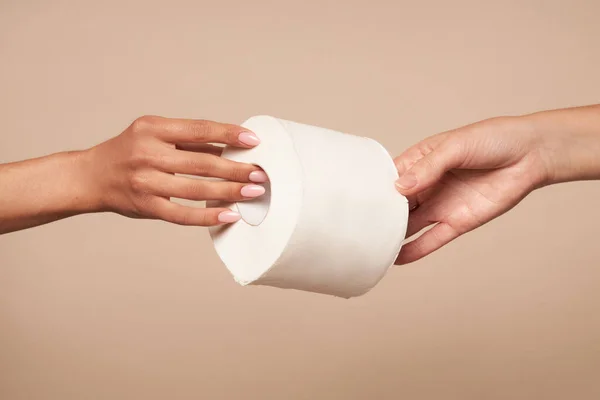 Higiene. As mãos femininas passam o papel higiênico a um contexto bege. Higiene diária para a prevenção de infecções virais e bacterianas . — Fotografia de Stock