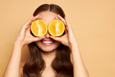 Güzellik. Işıl ışıl yüzü ve turuncu portresi olan gülümseyen kadın. Güzel gülümseyen Avrupalı kız modeli, doğal makyajı, sağlıklı gülüşü ve parlayan nemli yüzü var..